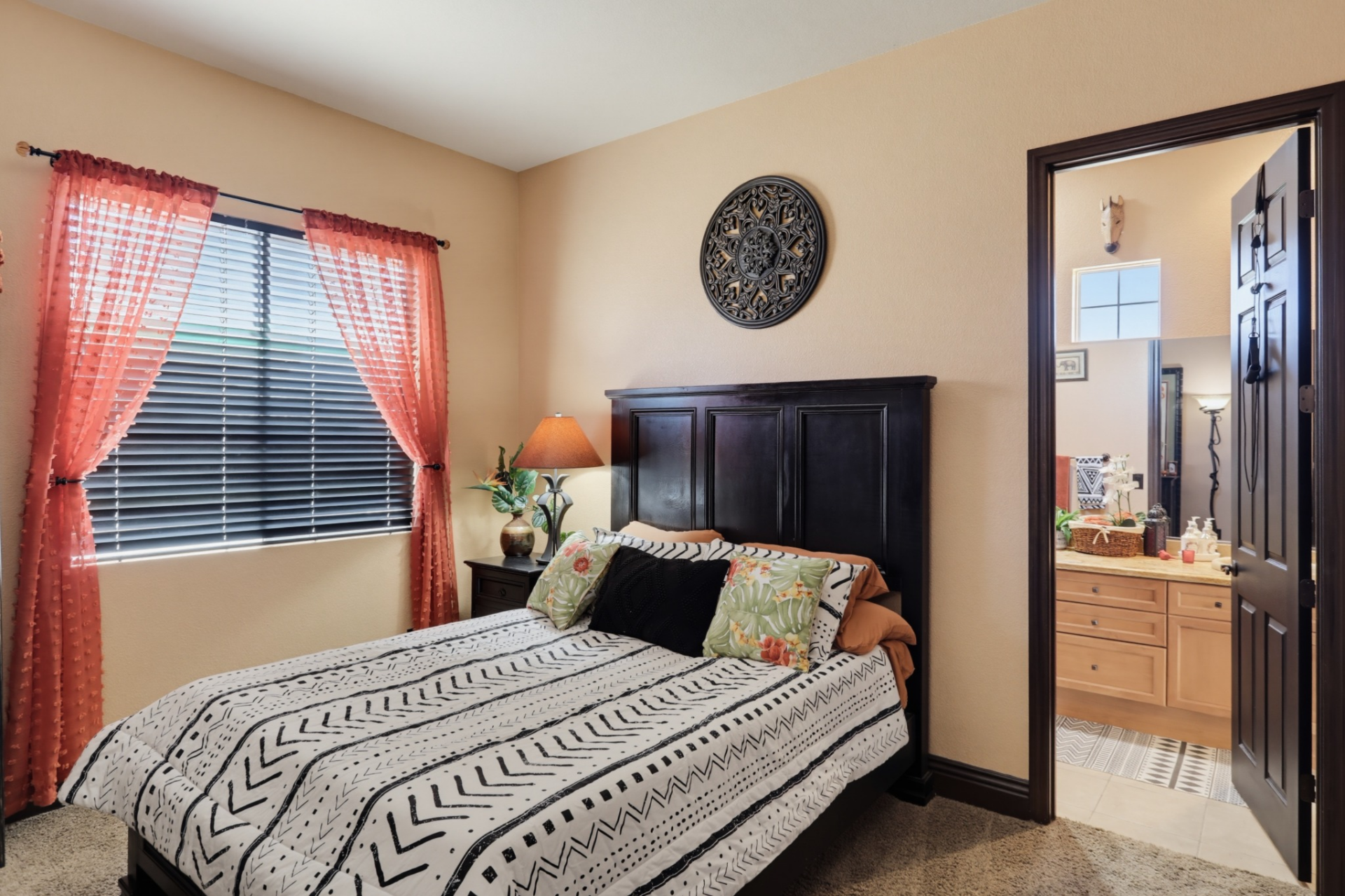 The first upstairs bedroom features warm tan walls, plush carpeting, and a dark wood bed frame that contrasts with the lighter finishes. 