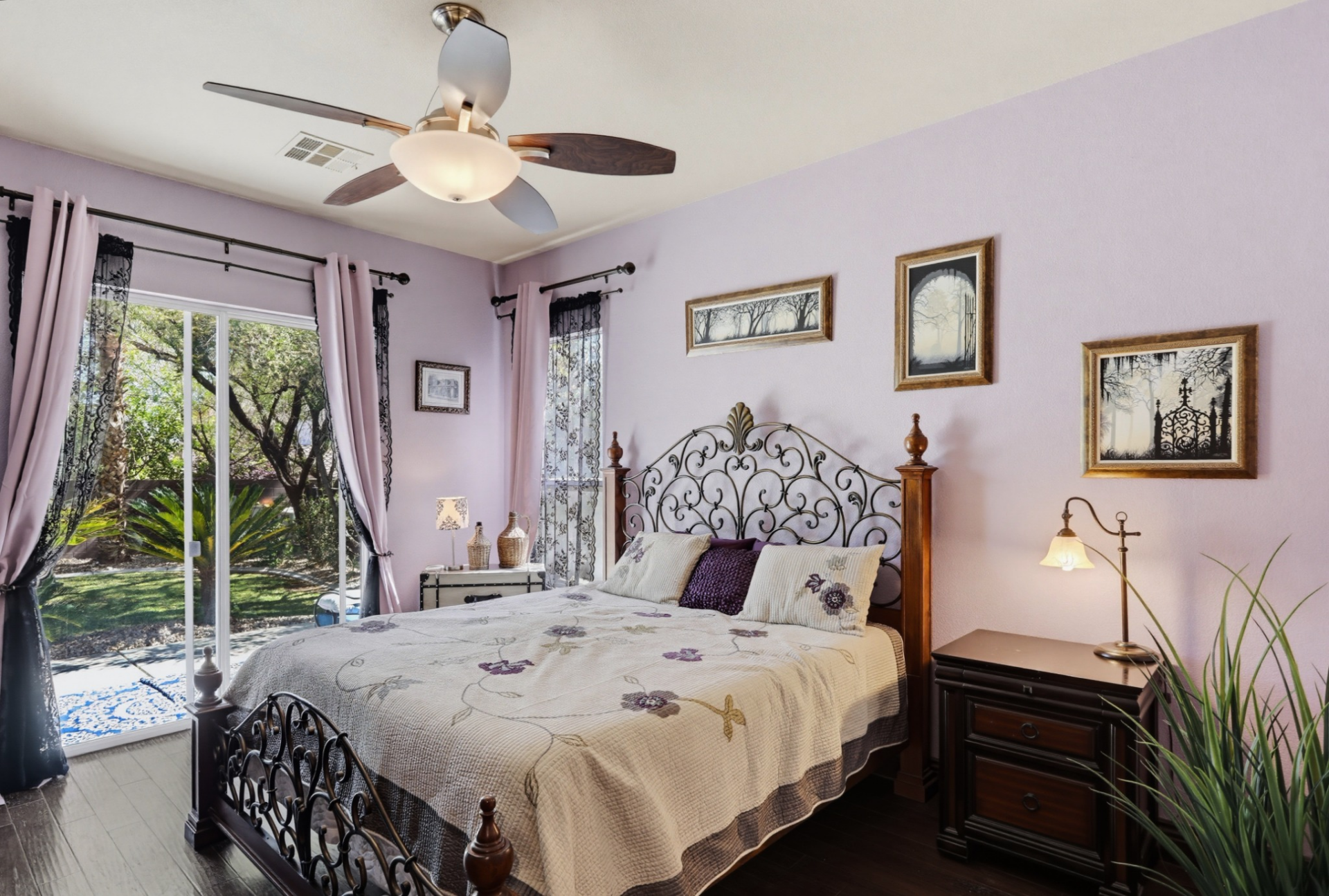 Located on the main level, the third bedroom is finished with lavender walls, dark hardwood flooring, and decorative wrought-iron bed frames.