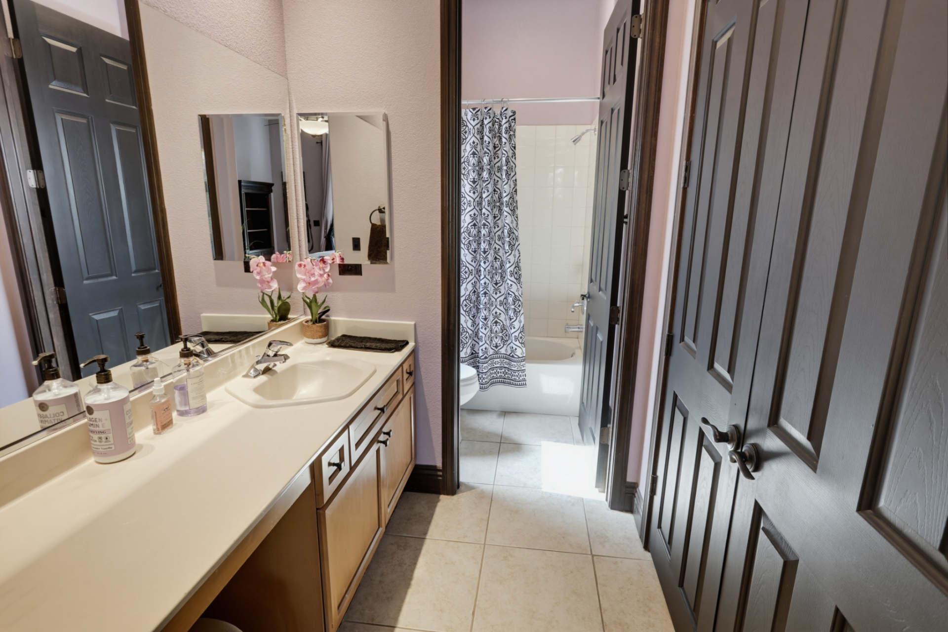 The attached bathroom includes a long single-sink vanity with lots of counter space, while the tub and shower are positioned in a separate room.