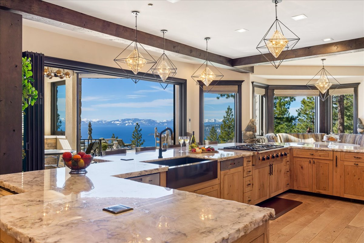 Retractable glass doors open directly to the covered outdoor kitchen, allowing the lake views to remain part of the cooking experience from nearly every angle.