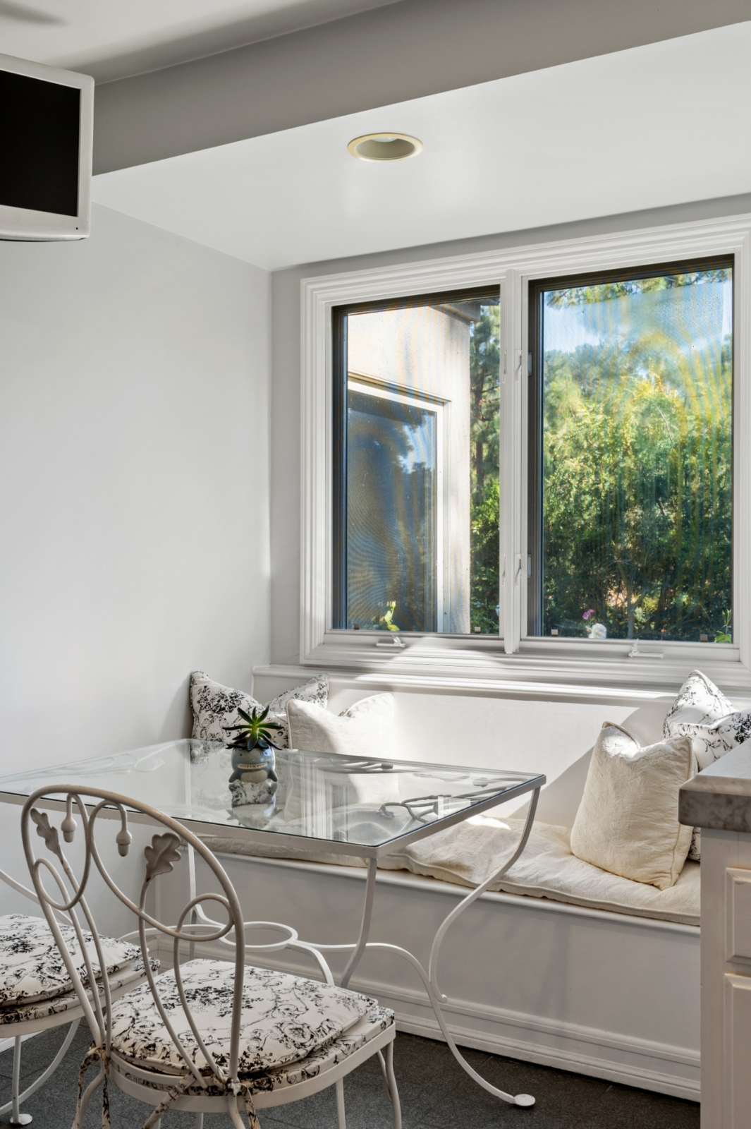A built-in breakfast nook pairs a cushioned window bench with a glass-top table.