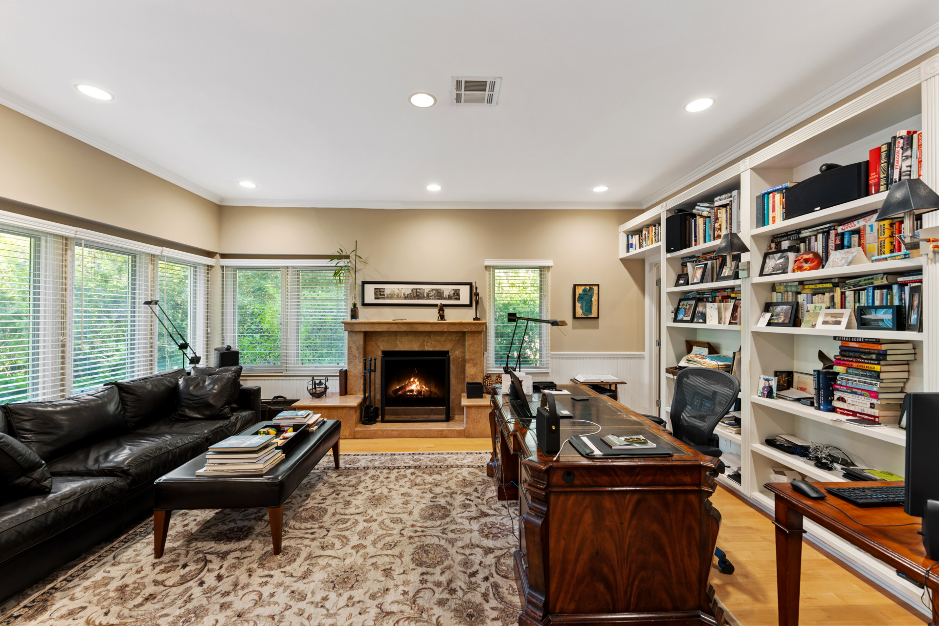 Office centered around a dark wood desk and a fireplace framed in stone.