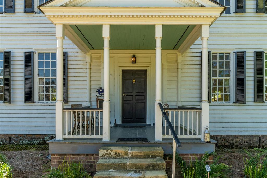 The front porch showcases the restrained elegance of Colonial craftsmanship with its simple pediment, slender columns, and original paneled front door.