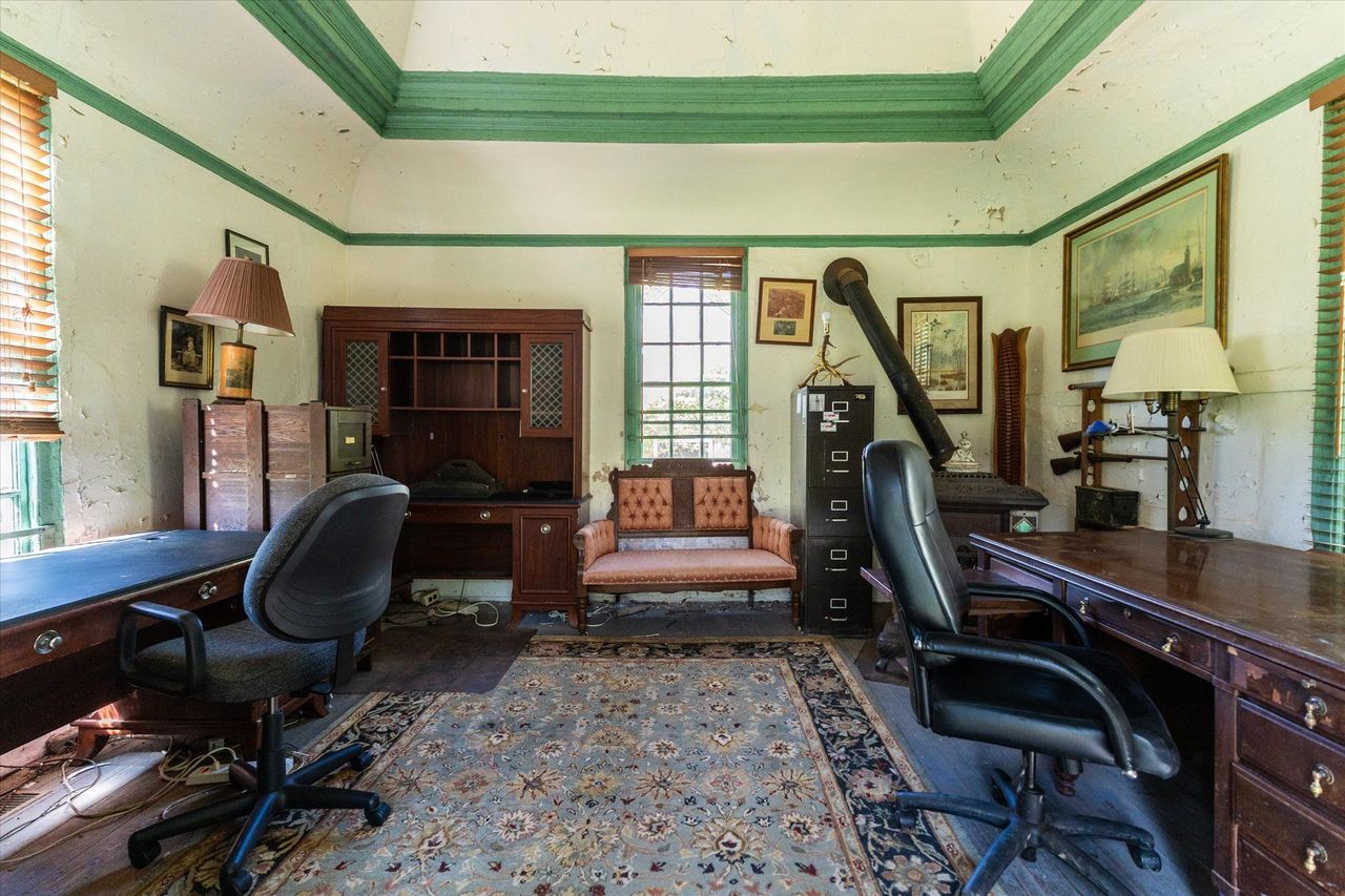 Two large desks sit opposite one another beneath tall period windows.