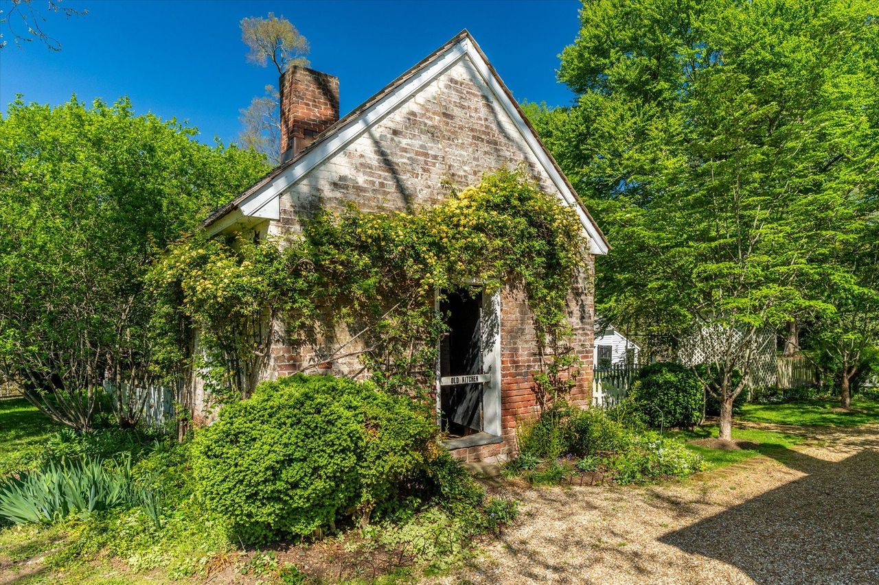 The estate's original detached kitchen still stands with its weathered brick walls softened by climbing vines.