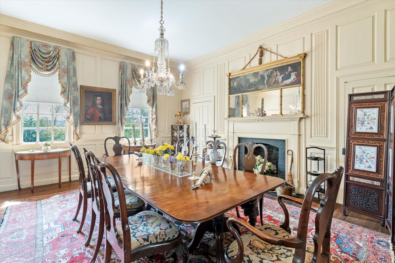 A long polished dining table sits in the middle, while large sash windows fill the space with natural light.