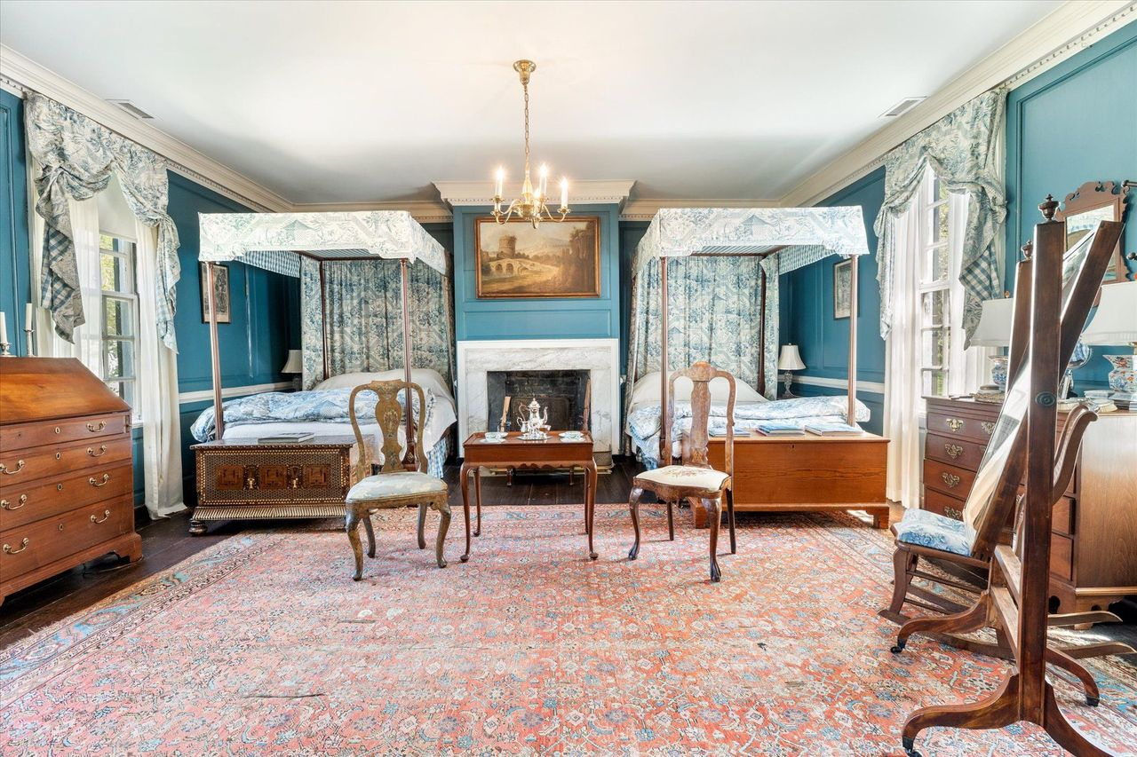 The blue bedchamber is one of the home's most beautiful sleeping quarters, with painted paneled walls, a marble fireplace, and matching four-poster canopy beds.