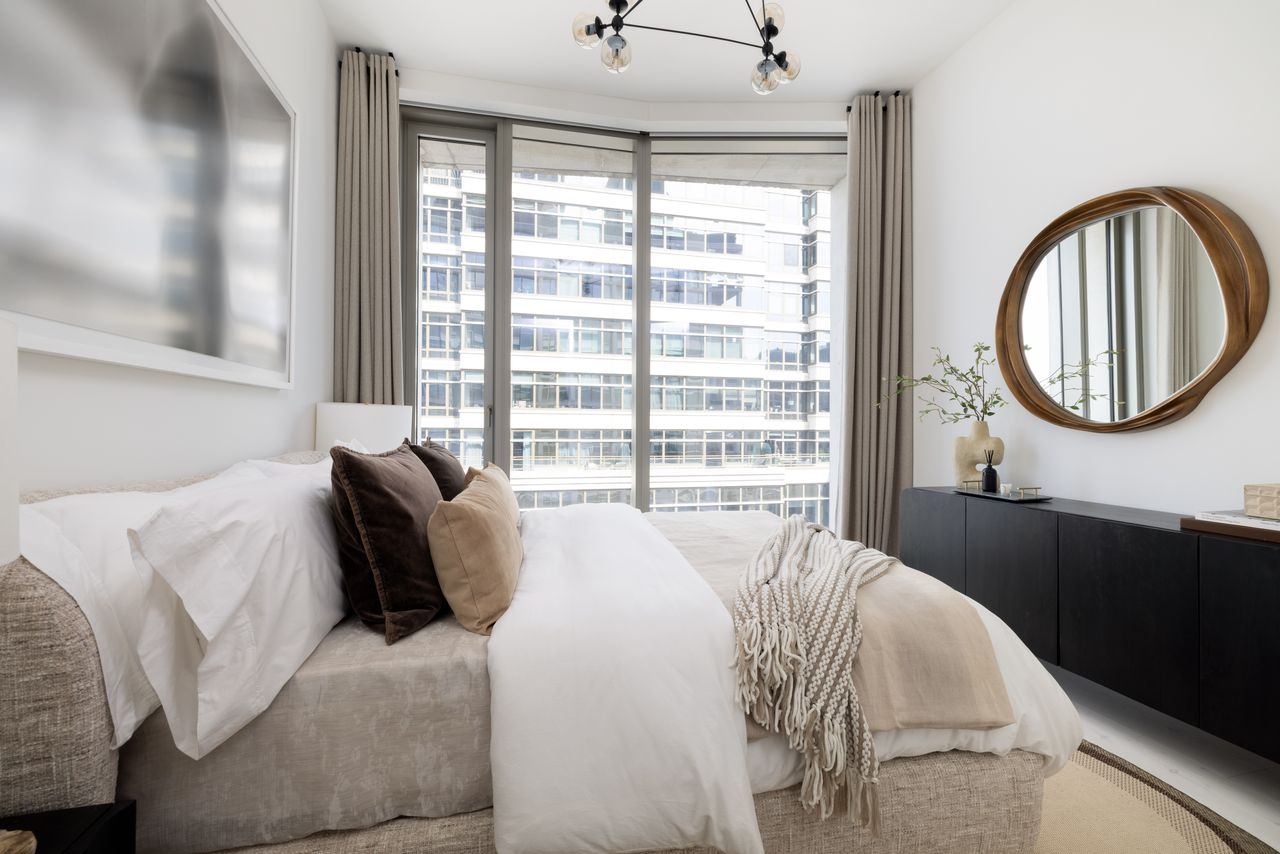 The guest bedroom pairs follow the same neutral palette as the rest of the home, brightened by tall windows.