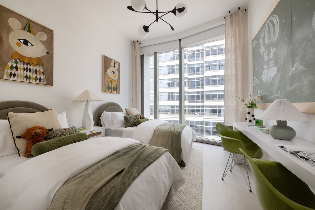 A children's room complete with two twin beds, playful artwork, built-in desks, and a custom chalkboard wall.
