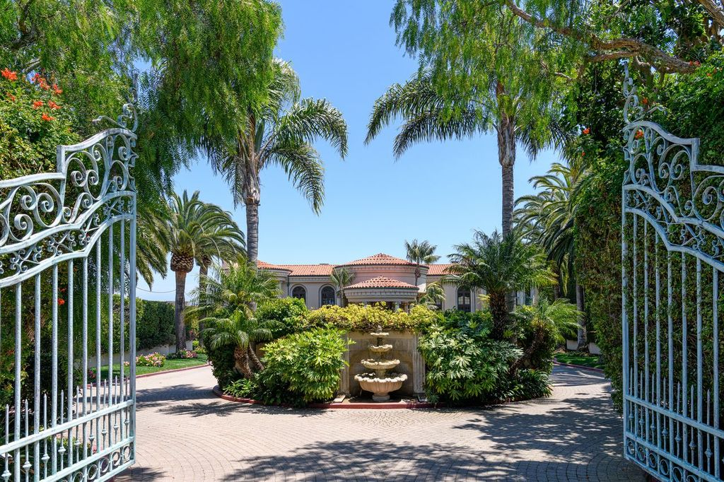 Passing through the wrought-iron gates, the driveway splits in two as it curves around a landscaped center island filled with greenery.