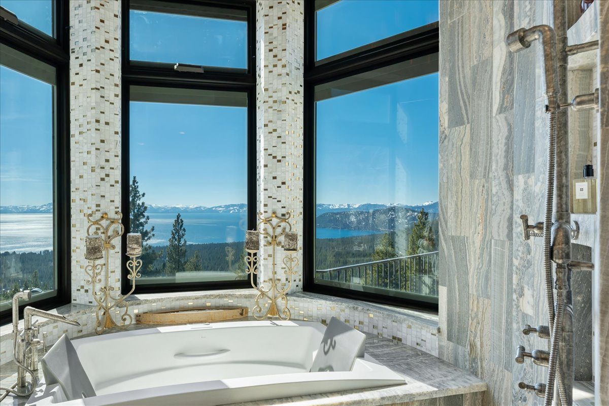 A soaking tub is positioned beside floor-to-ceiling windows overlooking Lake Tahoe.