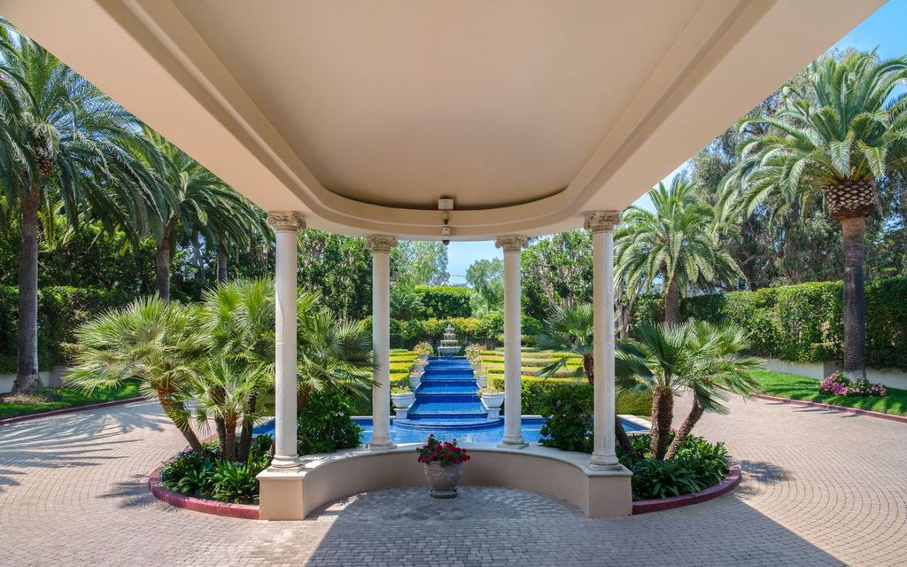 Both lanes lead toward a covered porte cochère supported by classical columns, where broad stone steps continue up to the front entrance. 