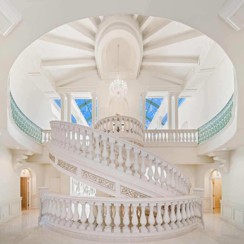 A soaring rotunda centered around a staircase that curves to an upper gallery. 