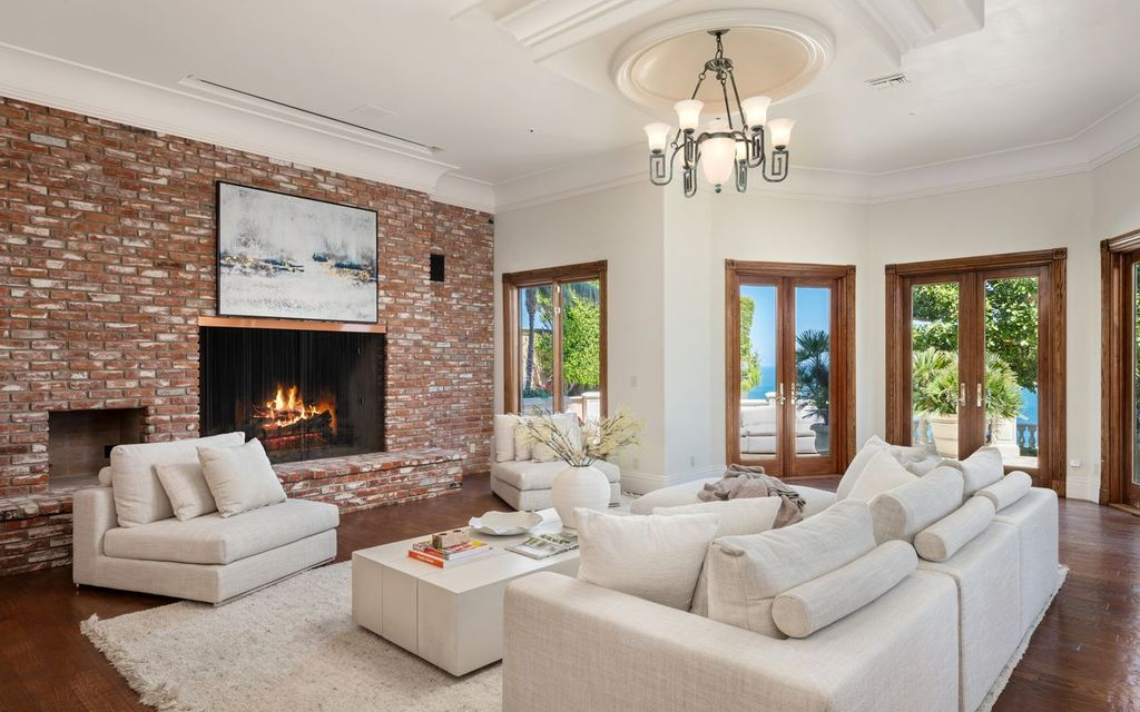 Across from the brick fireplace is a large sectional, while French doors fill the room with natural light and open directly onto the terrace.