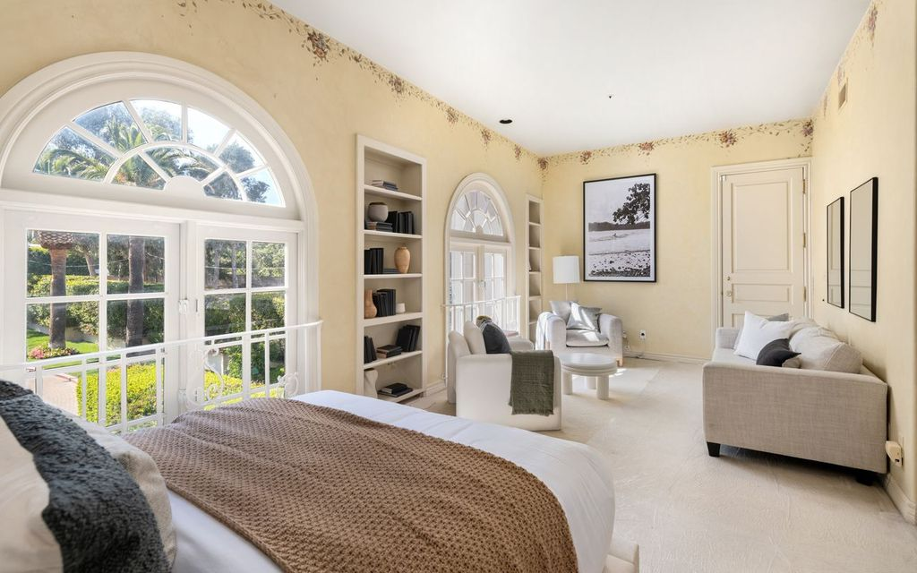 Another bedroom overlooks the estate's green grounds through a pair of arched windows. 