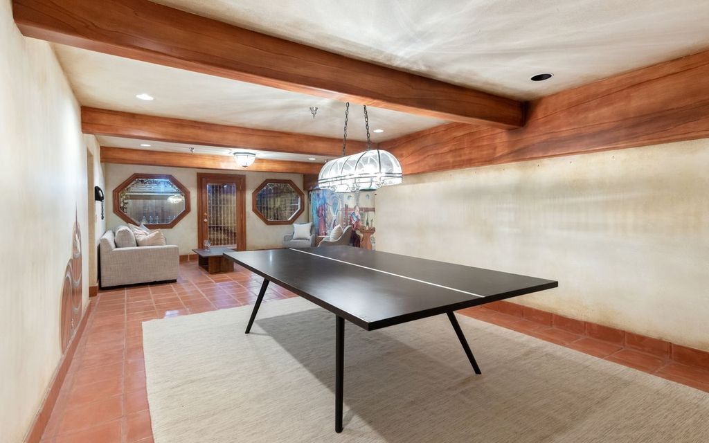 A long tasting table sits at the center beneath suspended pendant lighting, while seating at the far end creates a casual spot for private tastings surrounded by wood beams and terracotta floors.