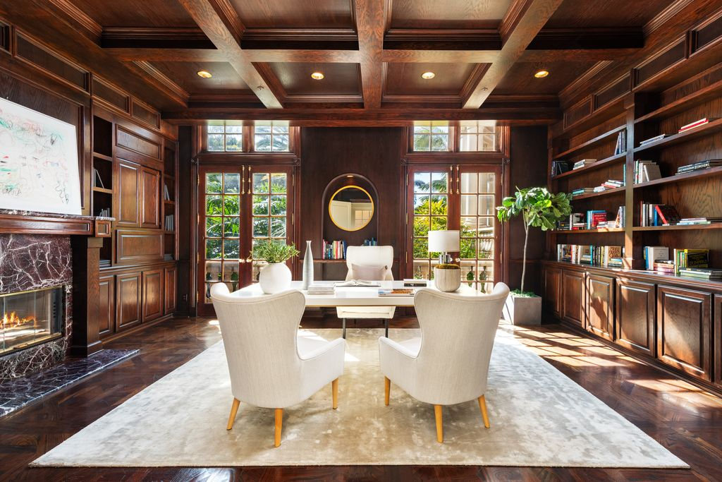 One of the home's private offices is wrapped in dark wood paneling with matching built-in bookcases lining the walls. 