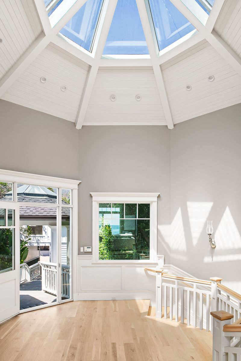 Stepping inside, you're greeted by a sunlit foyer beneath a skylight, where the vaulted ceiling, light oak floors, and open staircase.