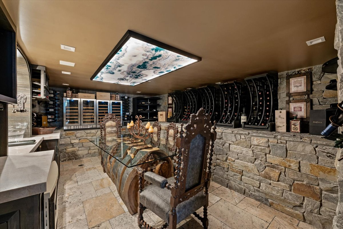 The wine cellar has native stone covering the walls and flooring, while temperature-controlled curved wine racks and dual wine refrigerators wrap around the room. 