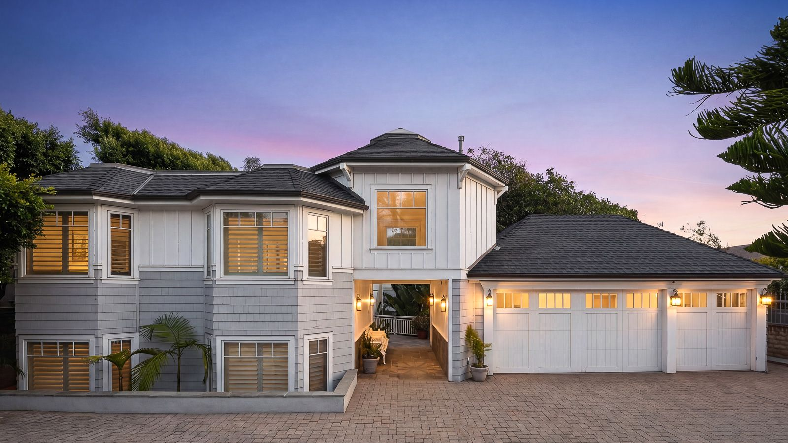 The detached three-car garage and guest house sit at the front of the property, with an open breezeway beneath creating the passage to the main residence tucked behind. 
