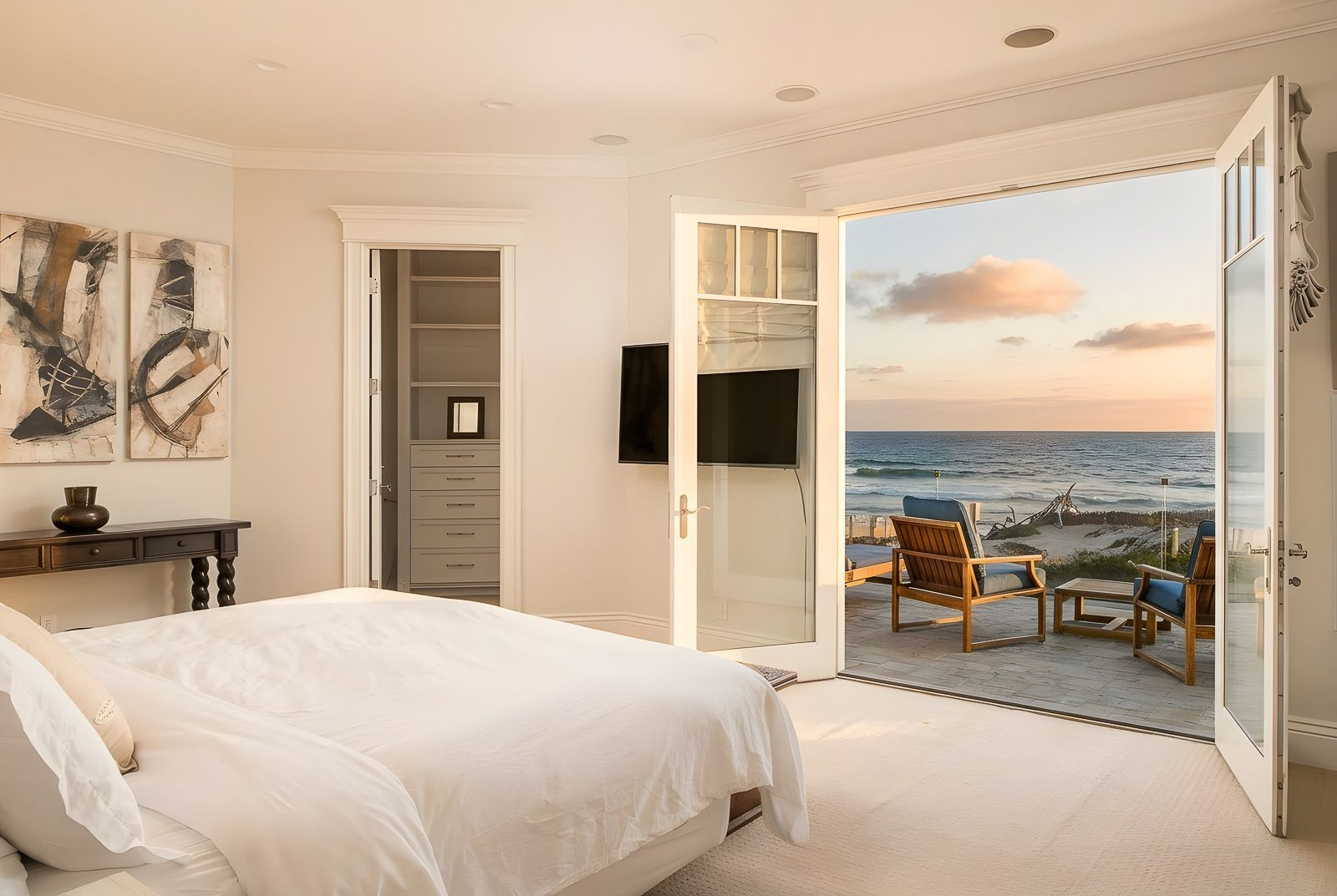 Bedroom with a relaxed coastal design with soft neutral finishes, and French doors that open directly onto a private oceanfront deck.