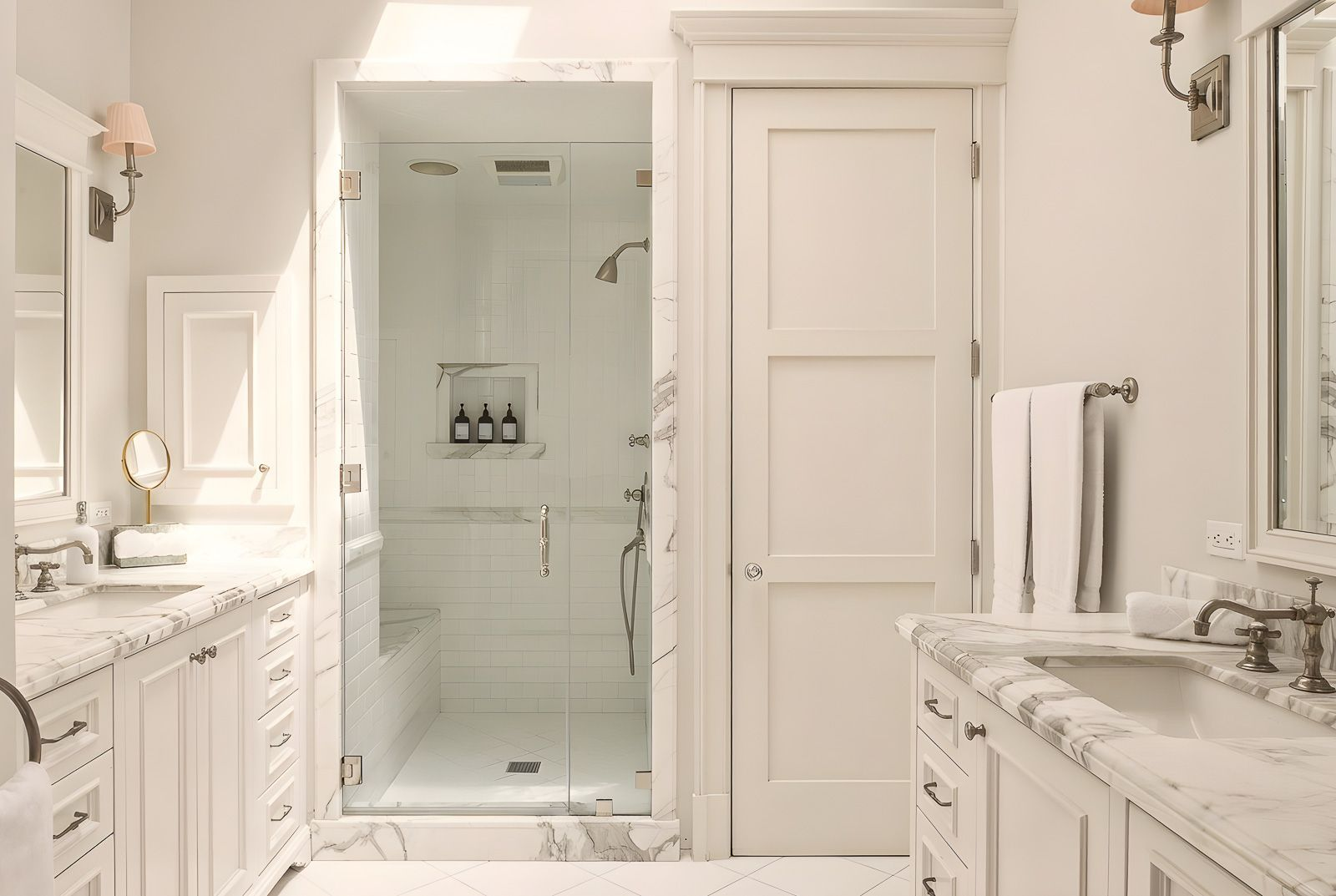 The suite's bathroom is lined with custom marble finishes across the dual vanities, a glass-enclosed steam shower, and a deep soaking tub.