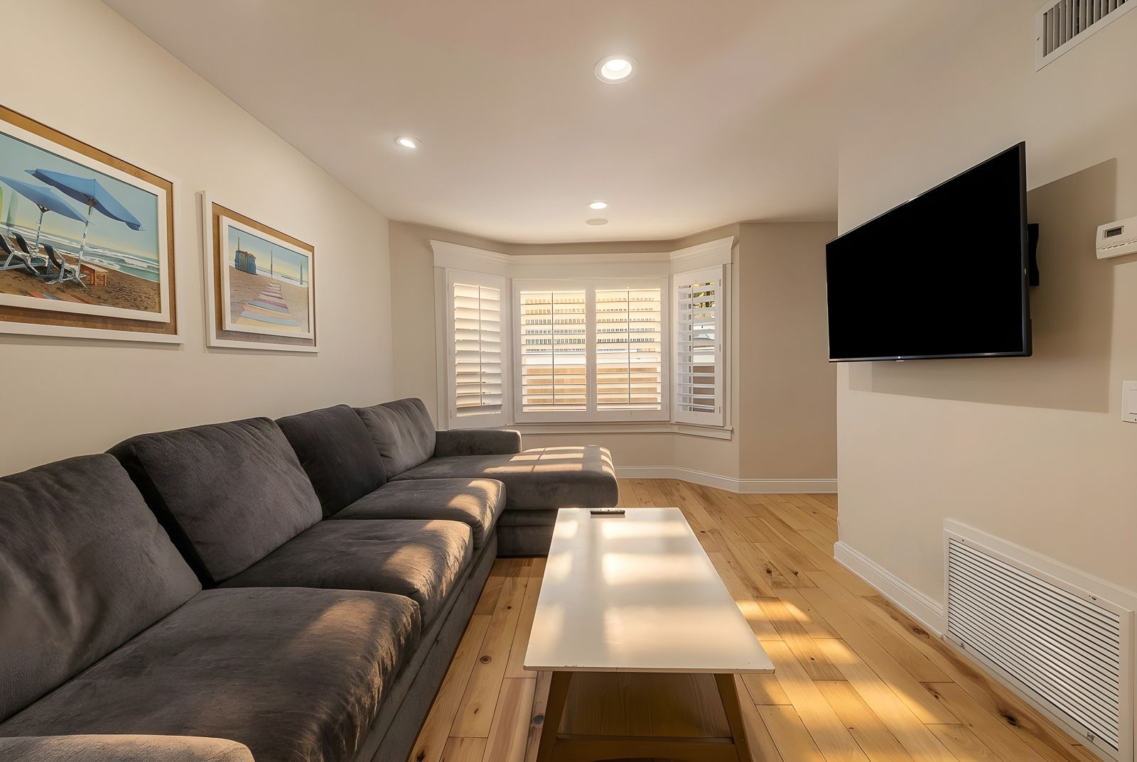 The living room offers a comfortable place to relax with wide-plank hardwood floors, plantation shutters, and built-in media space.