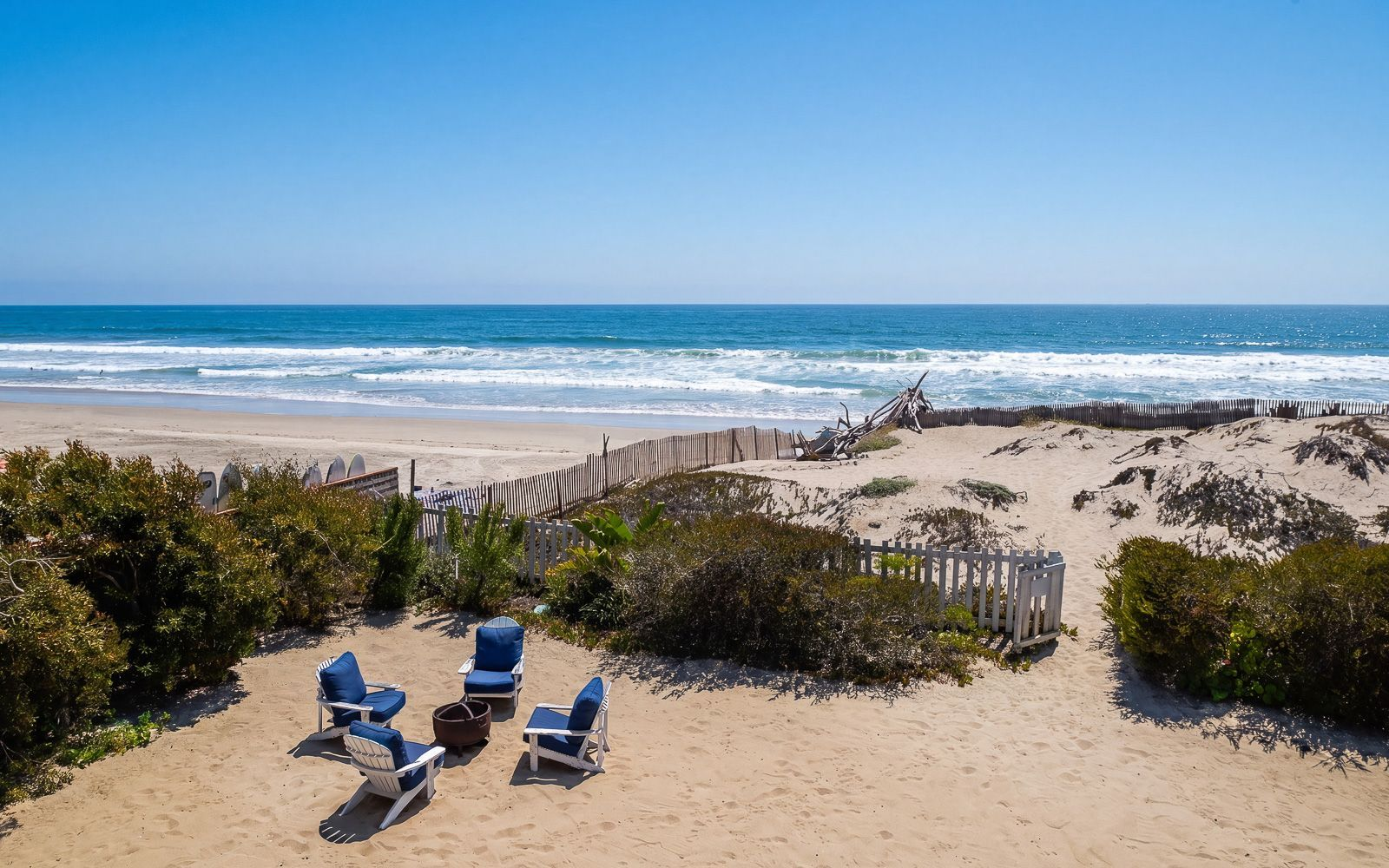 A gated path leads directly from the property to the beach, while the home's position captures panoramic views that stretch along the coastline.