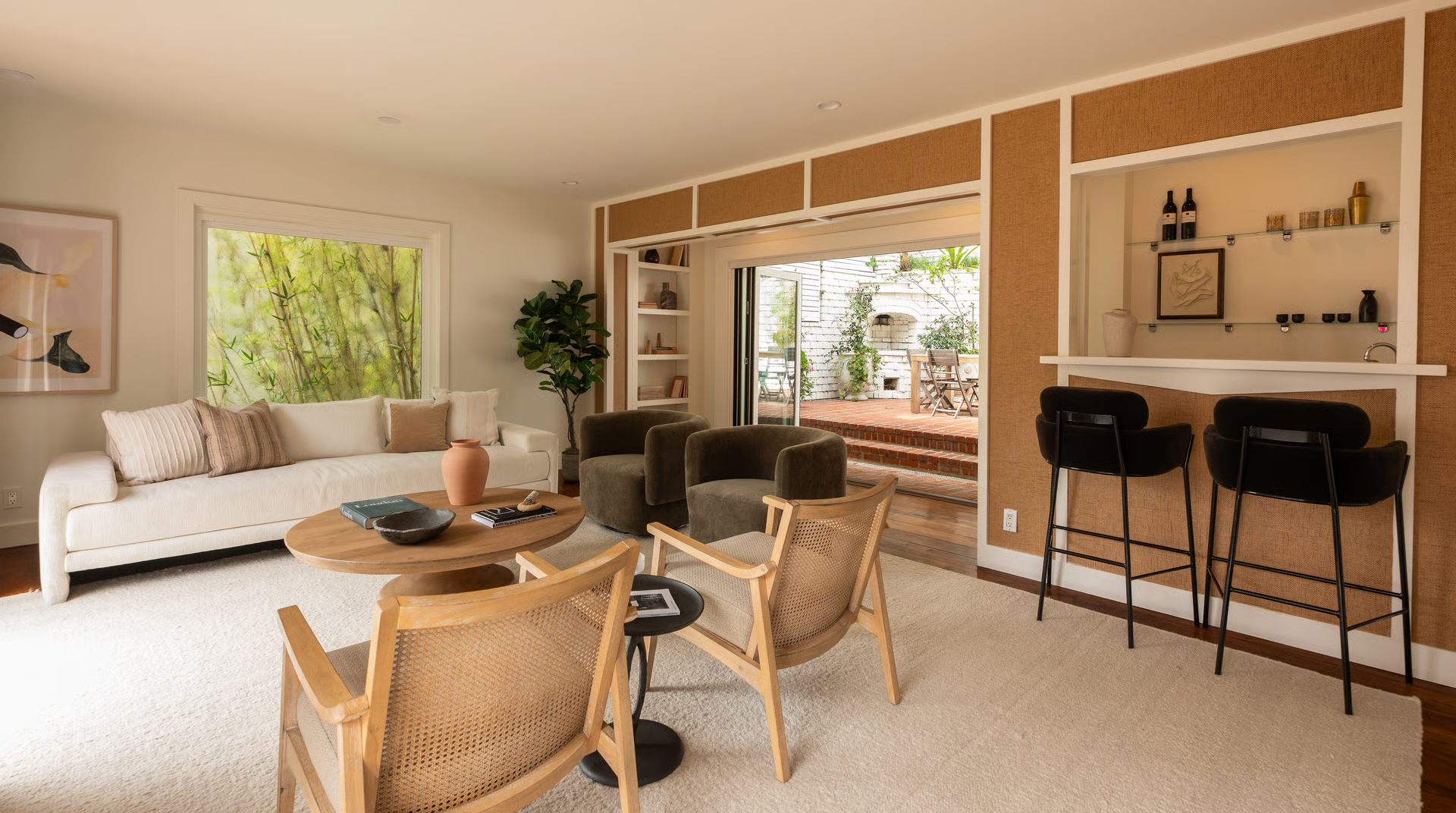 The main seating area is arranged around a round wooden coffee table, while a built-in wet bar tucked off to one side makes entertaining easy.
