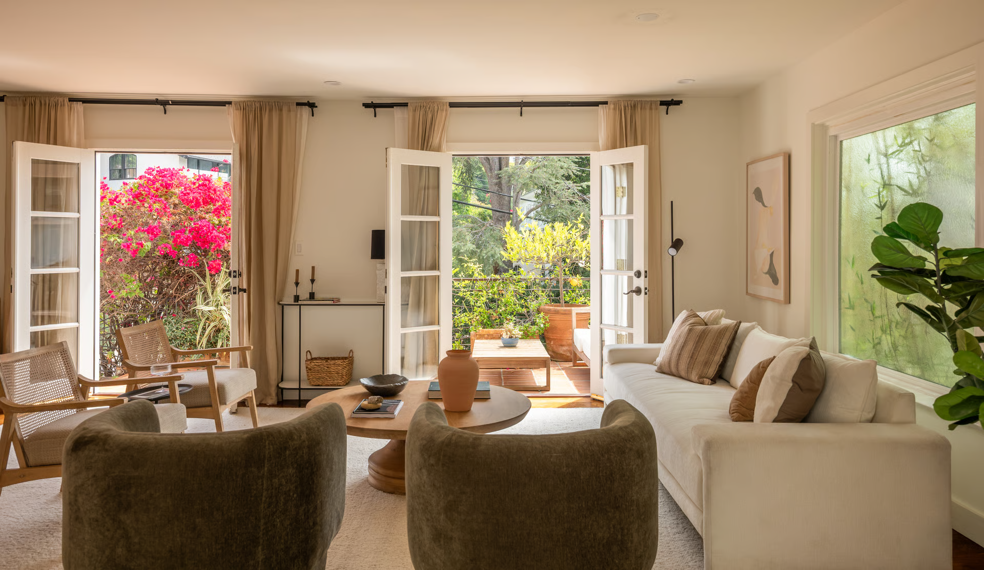 Stepping into the living room, soaring ceilings and oversized French doors immediately make the space feel bright and inviting, with the outdoor entertaining areas just beyond. 