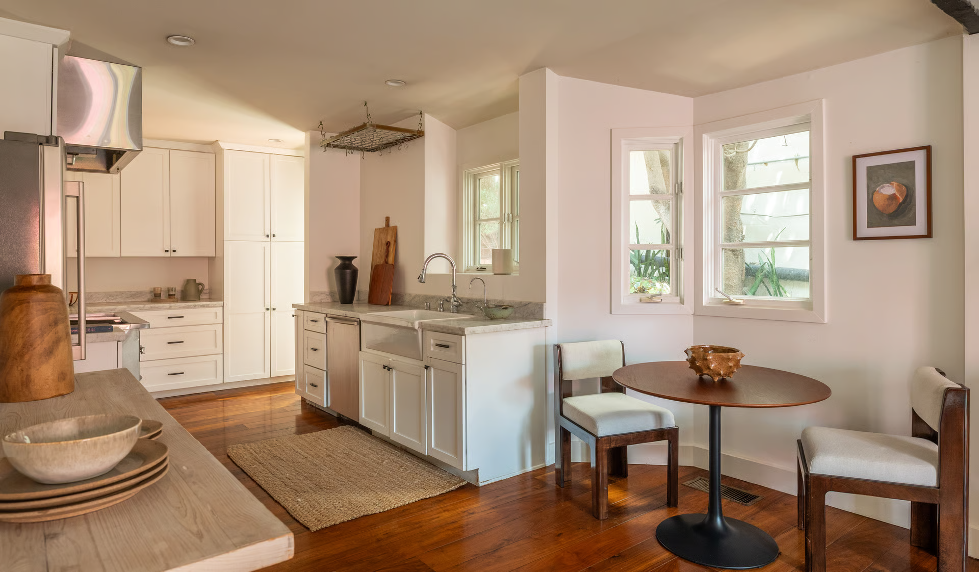 The chef's kitchen continues the home's warm design with white cabinetry, marble countertops, and rich hardwood floors.