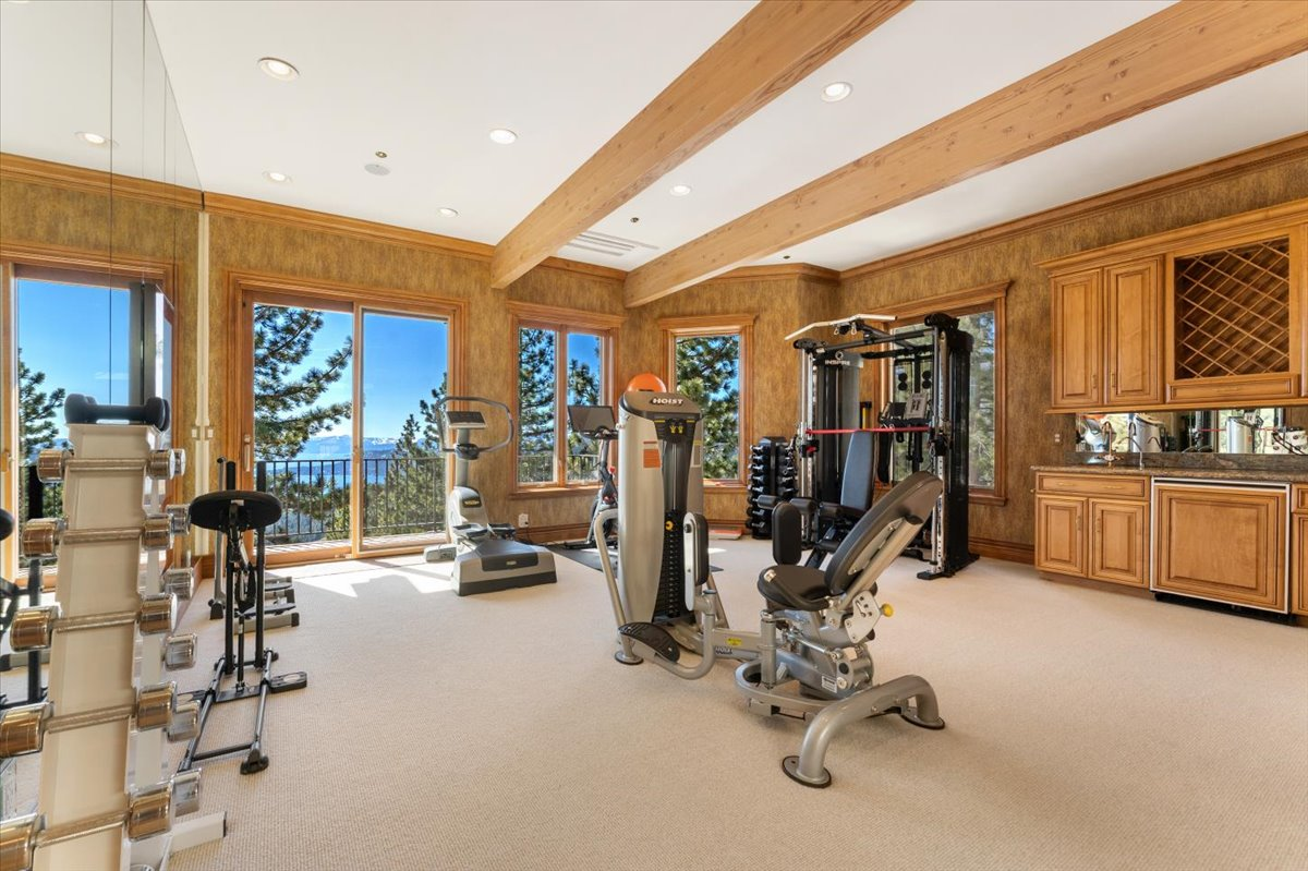 A fully equipped fitness center is surrounded by windows overlooking Lake Tahoe and opens onto a private balcony.