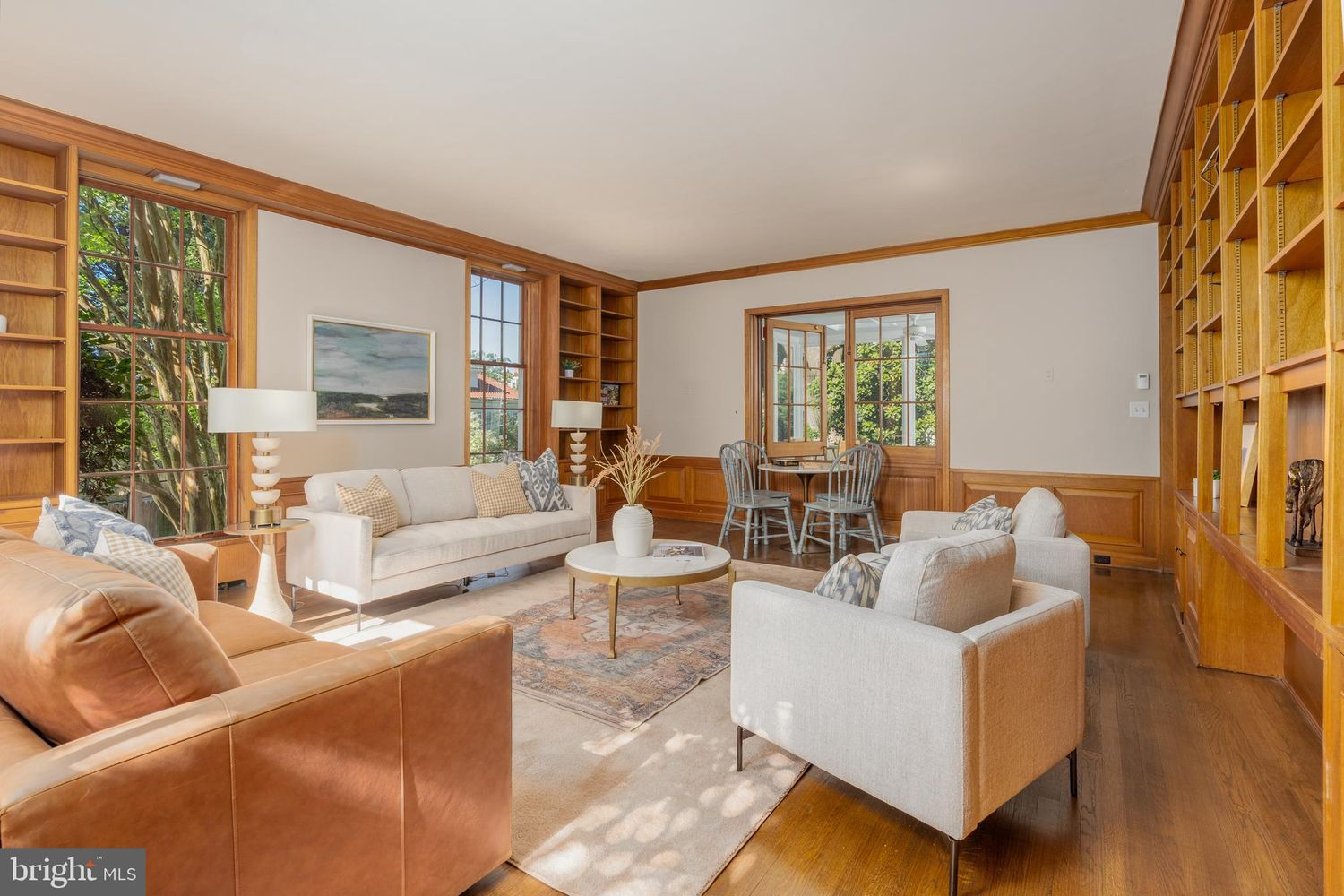 At the center of the room, a seating arrangement includes a pair of sofas and armchairs gathered around a round coffee table atop a large area rug.