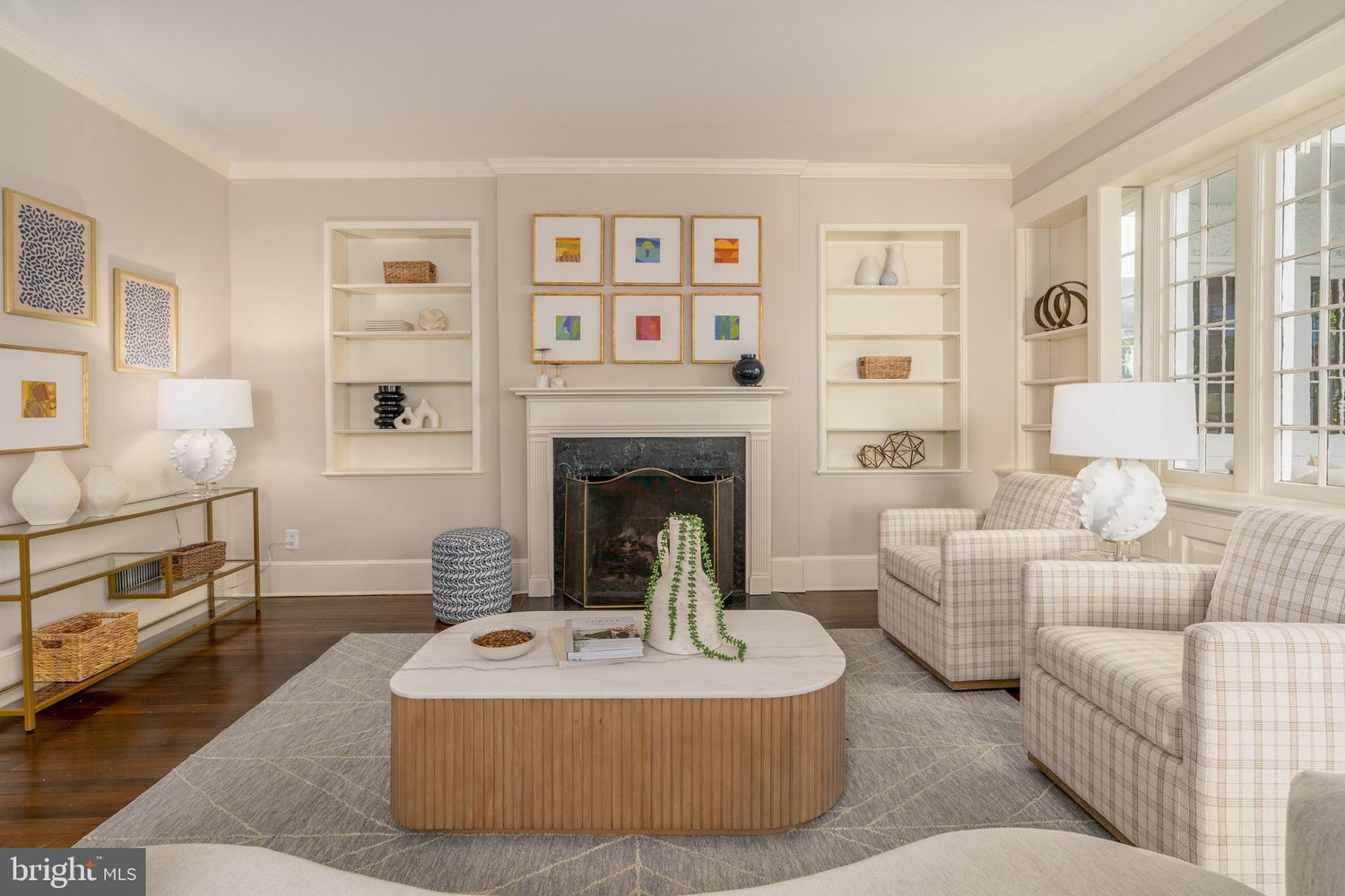A traditional fireplace serves as the room's focal point, framed by built-in display shelves and topped with a simple mantel that lets the home's original character take center stage.