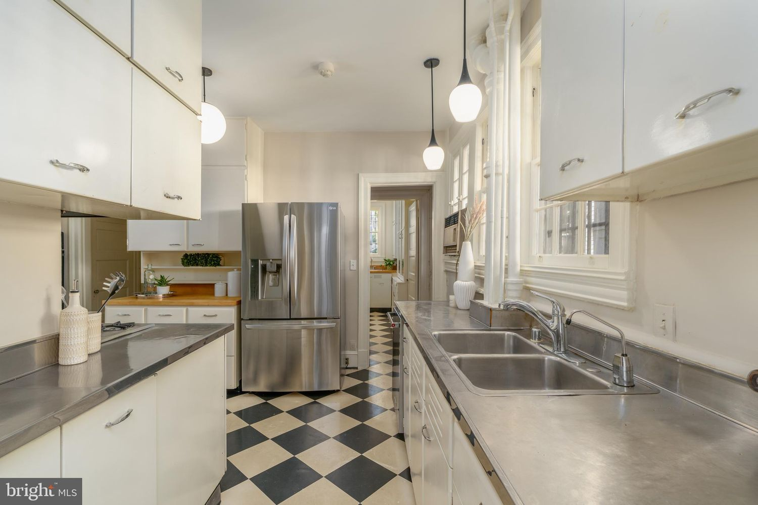 Stainless steel countertops frame both sides of the room with matching updated appliances integrated alongside the vintage cabinetry.