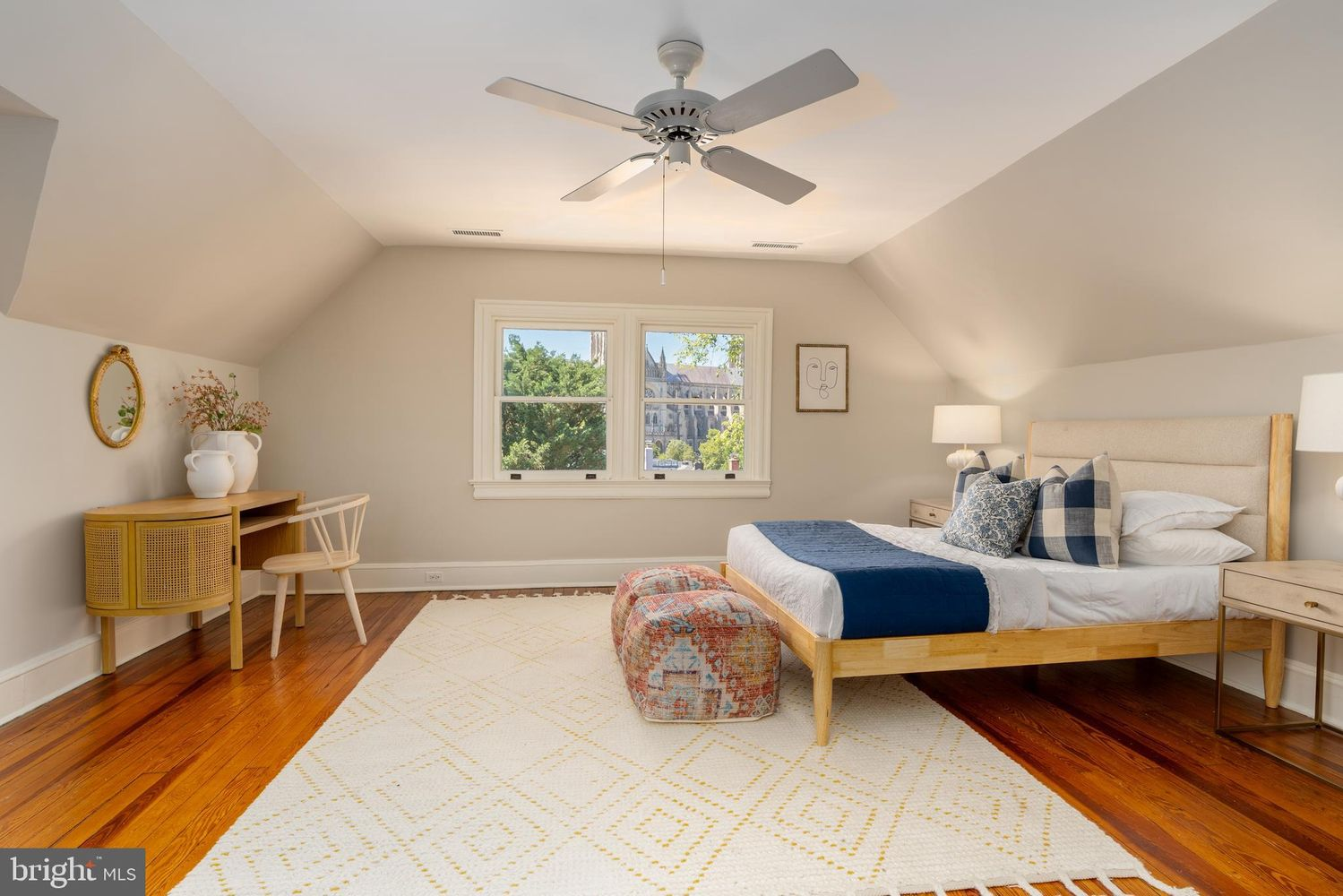 The placement of this room provides views of Washington National Cathedral rising above the surrounding trees, which stands out against the room's crisp white bedding and soft blue accents.