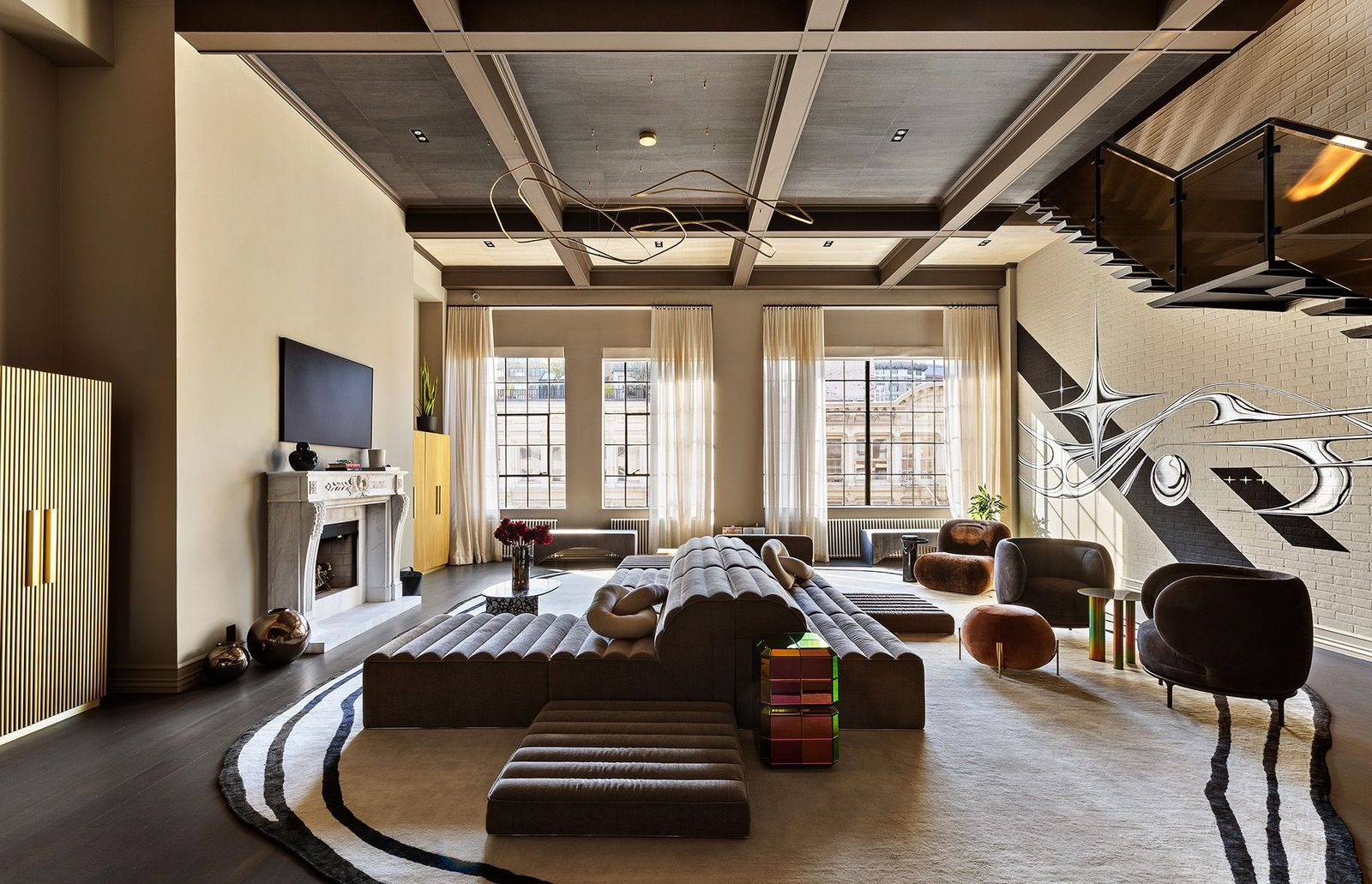 Stepping into the great room, 15-foot ceilings rise overhead beside original steel casement windows, exposed painted brick walls, and an impressive 53 feet of frontage overlooking West Broadway.