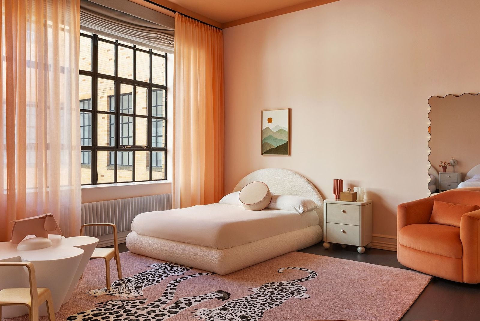An upholstered bed in a pink and orange colored room.