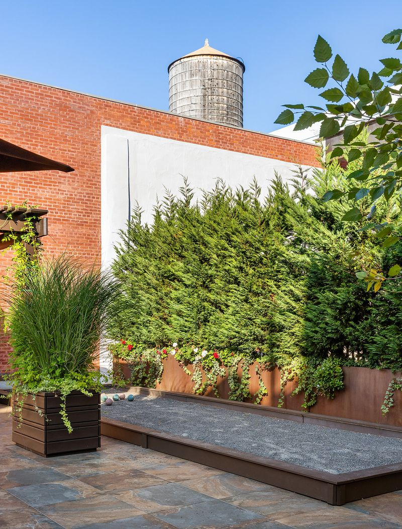 A private bocce court tucked next to a row of evergreens.