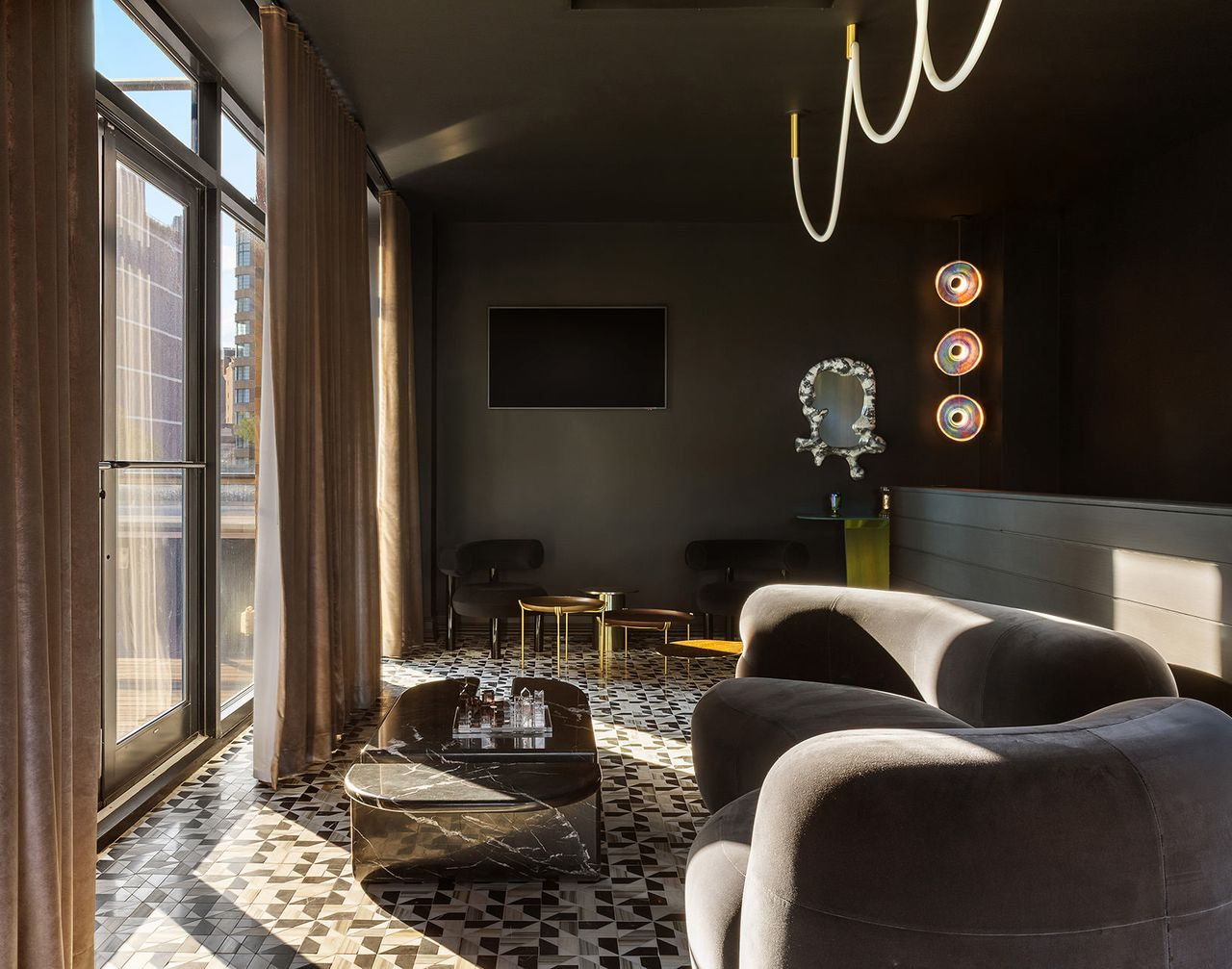 The lounge embraces a darker, more intimate palette with charcoal walls and ceilings, geometric black-and-white tile flooring, and sculptural contemporary furnishings.