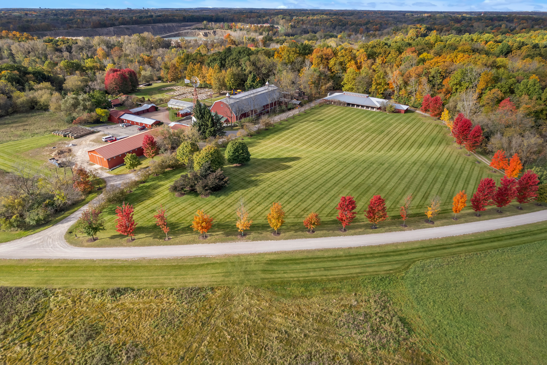 Beyond the main buildings, the property opens to a private baseball field spread out across a broad open space lined with Fall colored trees.