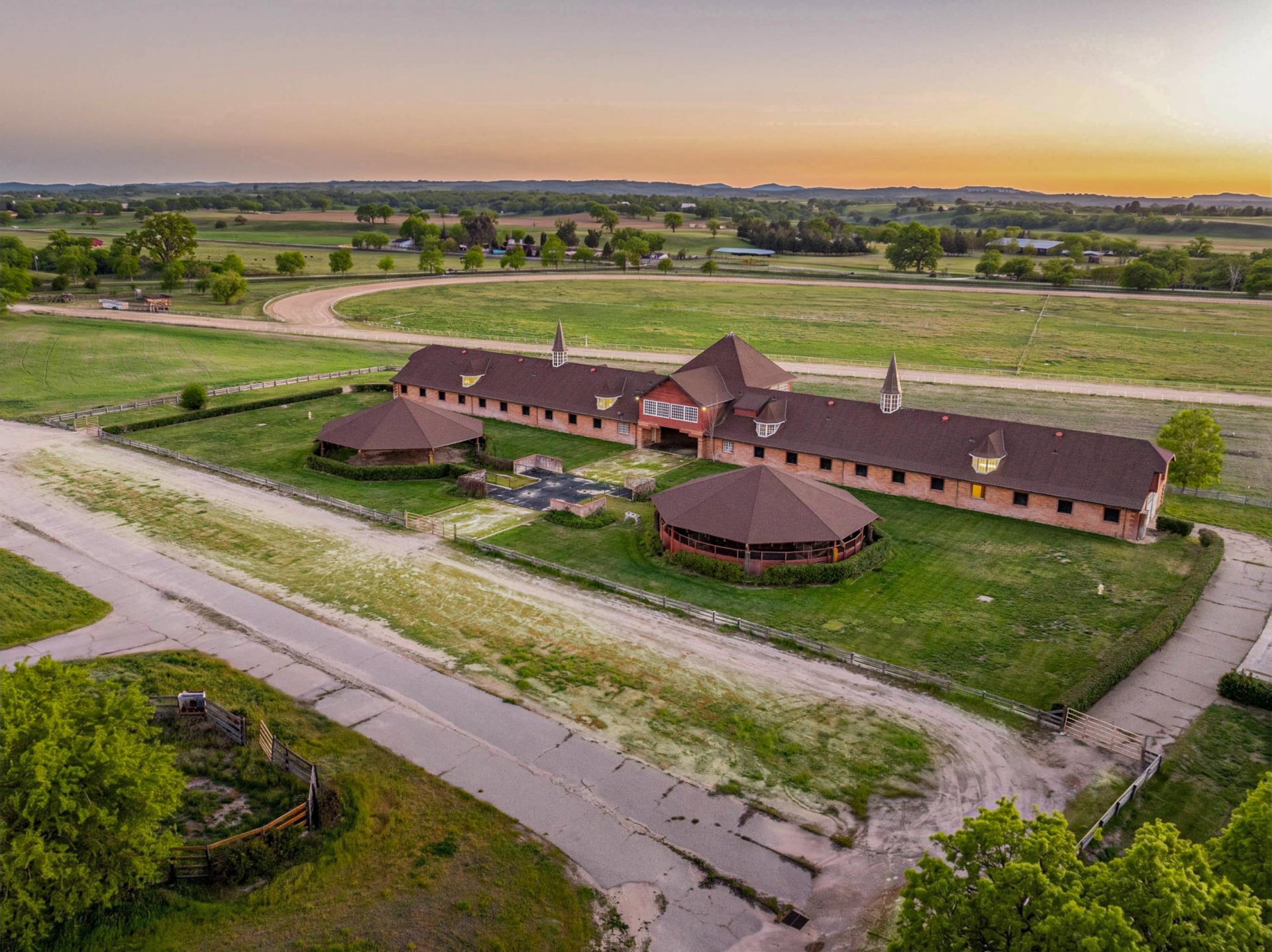 Paddoack barn in front of a Kentucky-style 6.5-furlong racetrack.