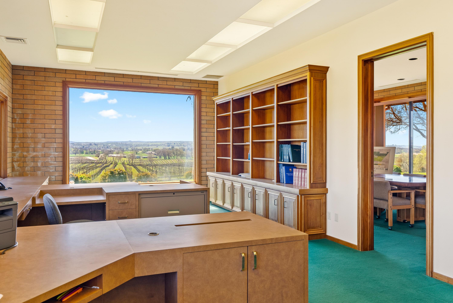 On an upper level of the home, the office is arranged around a multi-use built-in desk, with wood shelving and lower cabinets filling one wall for storage. 