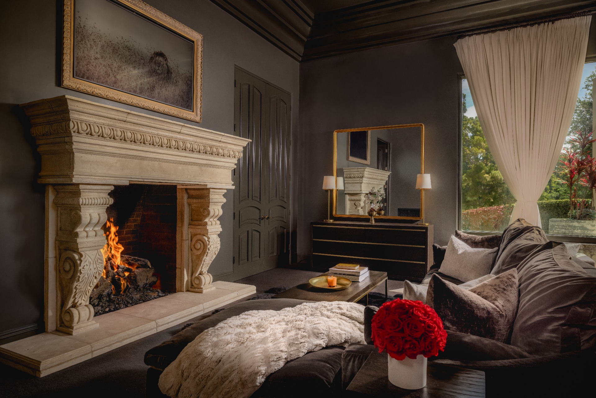 The suite's living area is surrounded by the same dark finishes, with a more relaxed sitting area arranged around a carved stone fireplace. 