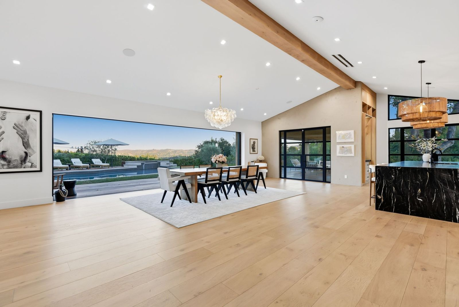 A long wood table is positioned beneath a sculptural glass chandelier, for some of the best views in the house.