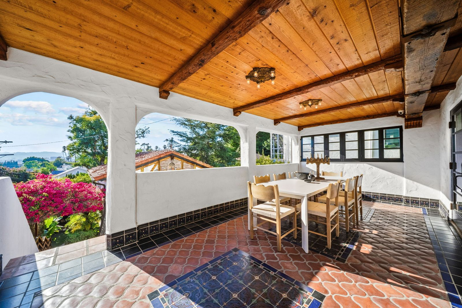 Just outside the kitchen, doors open directly onto a covered outdoor dining patio with a wood-plank ceiling and Spanish tile flooring.