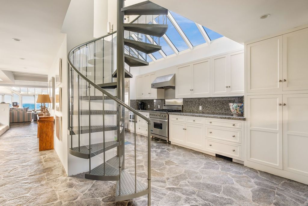 Beside the kitchen, a spiral staircase rises through the center of the floor plan to the bedroom level above.