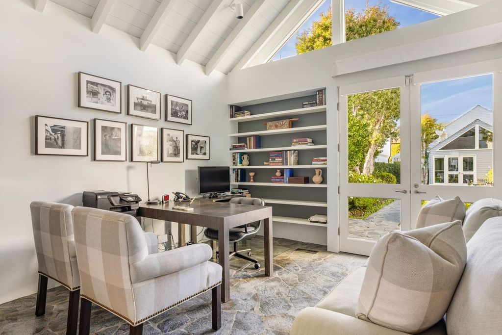 A desk faces a wall of built-in shelving placed next to glass doors that open directly to the property’s central courtyard.