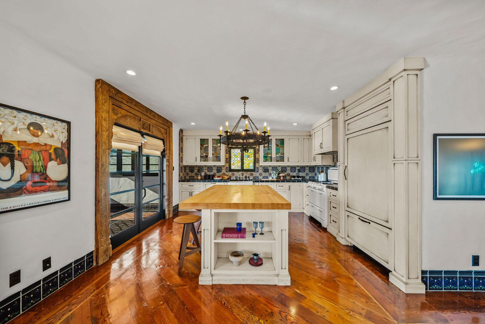 The kitchen pairs cream-colored cabinetry and colorful hand-laid tile backsplashes with updated appliances. 
