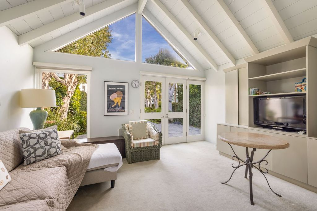 The guest house opens past French doors, with a daybed, wicker chair, round table, and built-in media cabinetry.